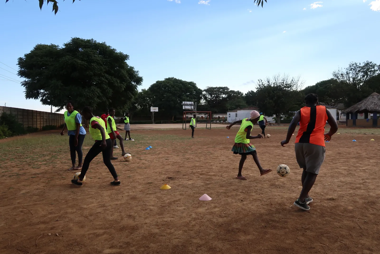 Children training with a football and cones on a dirt pitch in Lusaka, Zambia